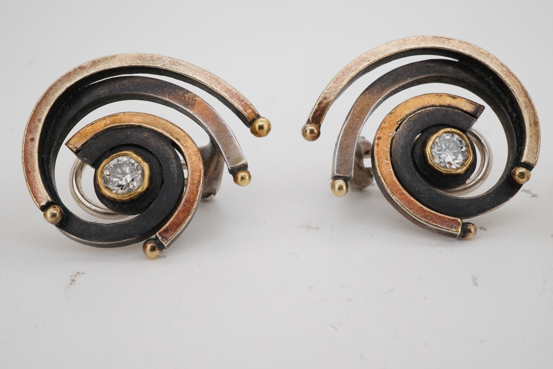 Two pairs of diamond earrings, comprising: one pair of woven design, set with brilliant-cut diamonds totalling approximately 0.10 carats, mounted in bicoloured 18ct gold, length 2.4cm each, post fittings, British hallmar